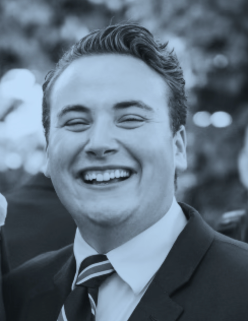 Andy Burnim, smiling, wearing a dark suit and striped tie.